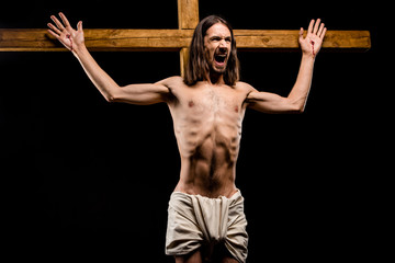 shirtless man crucified on wooden cross screaming isolated on black - obrazy, fototapety, plakaty
