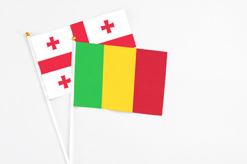 Mali and Georgia stick flags on white background. High quality fabric, miniature national flag. Peaceful global concept.White floor for copy space.