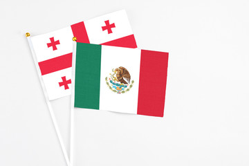 Mexico and Georgia stick flags on white background. High quality fabric, miniature national flag. Peaceful global concept.White floor for copy space.