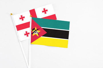 Mozambique and Georgia stick flags on white background. High quality fabric, miniature national flag. Peaceful global concept.White floor for copy space.
