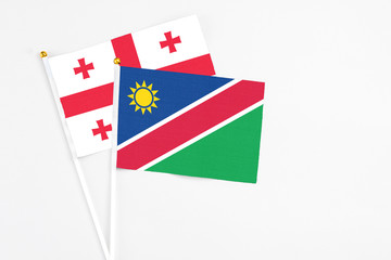 Namibia and Georgia stick flags on white background. High quality fabric, miniature national flag. Peaceful global concept.White floor for copy space.