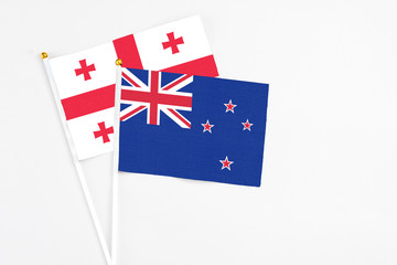 New Zealand and Georgia stick flags on white background. High quality fabric, miniature national flag. Peaceful global concept.White floor for copy space.