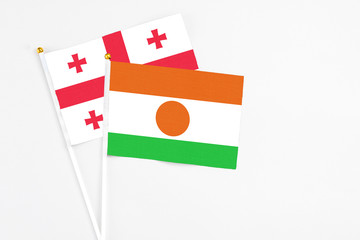 Niger and Georgia stick flags on white background. High quality fabric, miniature national flag. Peaceful global concept.White floor for copy space.