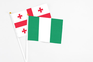 Nigeria and Georgia stick flags on white background. High quality fabric, miniature national flag. Peaceful global concept.White floor for copy space.