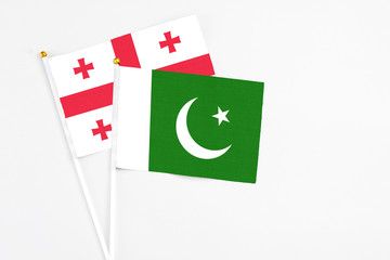 Pakistan and Georgia stick flags on white background. High quality fabric, miniature national flag. Peaceful global concept.White floor for copy space.