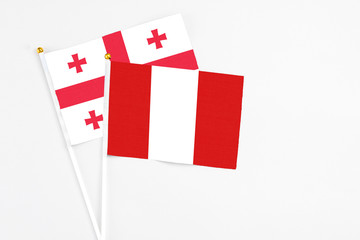 Peru and Georgia stick flags on white background. High quality fabric, miniature national flag. Peaceful global concept.White floor for copy space.