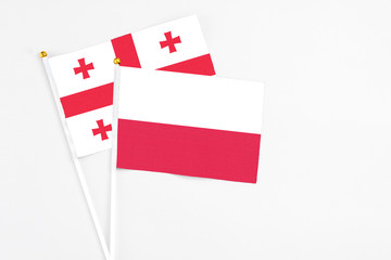 Poland and Georgia stick flags on white background. High quality fabric, miniature national flag. Peaceful global concept.White floor for copy space.