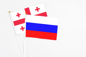 Russia and Georgia stick flags on white background. High quality fabric, miniature national flag. Peaceful global concept.White floor for copy space.