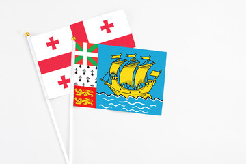 Saint Pierre And Miquelon and Georgia stick flags on white background. High quality fabric, miniature national flag. Peaceful global concept.White floor for copy space.