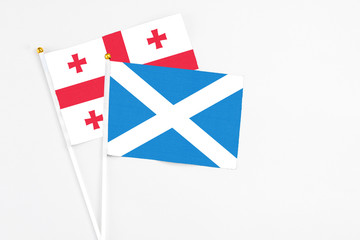 Scotland and Georgia stick flags on white background. High quality fabric, miniature national flag. Peaceful global concept.White floor for copy space.