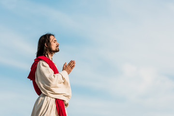 man with closed eyes praying against blue sly