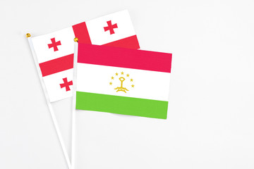 Tajikistan and Georgia stick flags on white background. High quality fabric, miniature national flag. Peaceful global concept.White floor for copy space.