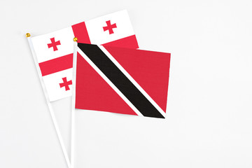 Trinidad And Tobago and Georgia stick flags on white background. High quality fabric, miniature national flag. Peaceful global concept.White floor for copy space.