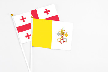 Vatican City and Georgia stick flags on white background. High quality fabric, miniature national flag. Peaceful global concept.White floor for copy space.