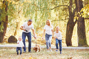Fototapeta premium Cheerful young family have a walk in an autumn park together
