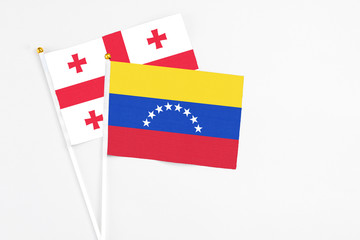 Venezuela and Georgia stick flags on white background. High quality fabric, miniature national flag. Peaceful global concept.White floor for copy space.