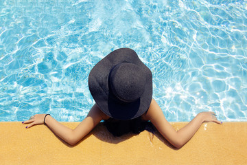 Fototapeta na wymiar Young beautiful girl in a hat by the pool, top view