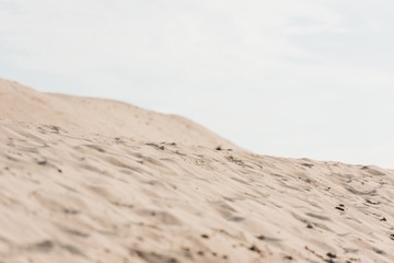 selective focus of wavy sand against sky with clouds in desert