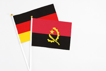Angola and Germany stick flags on white background. High quality fabric, miniature national flag. Peaceful global concept.White floor for copy space.
