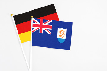 Fototapeta premium Anguilla and Germany stick flags on white background. High quality fabric, miniature national flag. Peaceful global concept.White floor for copy space.