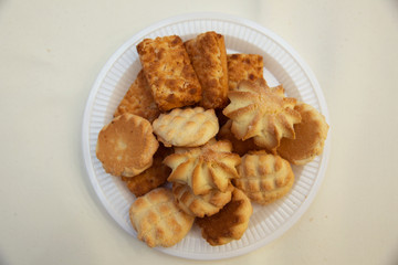 Oven fresh cookies and biscuits served in plate. baked toast garlic bread isolated on white background . variety of biscuit on plate isolated on white .