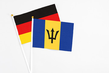 Barbados and Germany stick flags on white background. High quality fabric, miniature national flag. Peaceful global concept.White floor for copy space.