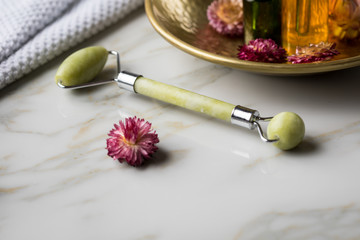 Massage Steinroller mit Naturkosmetik Beauty Öl Serum Flaschen an Handtuch, Gold Metall Schale und...