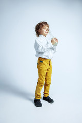 Pretty young boy in casual clothes on white studio background. Fashionable posing. Caucasian male preschooler with bright facial emotions. Childhood, expression, having fun. Drinking milk, smiling,