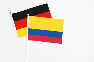 Colombia and Germany stick flags on white background. High quality fabric, miniature national flag. Peaceful global concept.White floor for copy space.