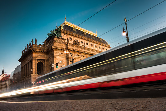 Motion blurred city electric tram in front of National Theatre, Prague Czech historic building and cultural icon with golden roof top garden UNESCO. Prague Transport System (PID) background