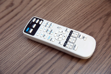 Remote controller . White projector System REMOTE Control wooden background. Projector console on a wooden table .