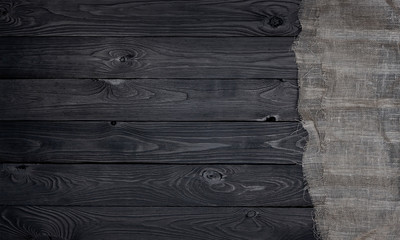 Old burlap fabric napkin on black wooden background, top view