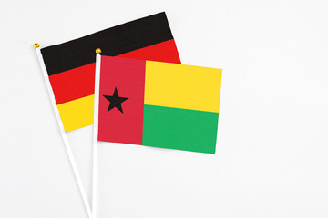 Guinea Bissau and Germany stick flags on white background. High quality fabric, miniature national flag. Peaceful global concept.White floor for copy space.