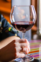 female hand holds a glass of red wine