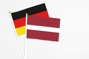 Latvia and Germany stick flags on white background. High quality fabric, miniature national flag. Peaceful global concept.White floor for copy space.