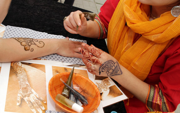 Artist applying henna tattoo on women hands. Mehndi is traditional Indian decorative art