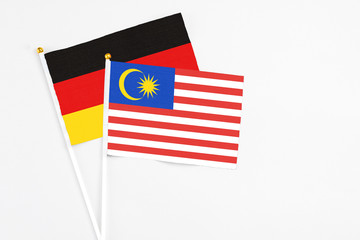 Malaysia and Germany stick flags on white background. High quality fabric, miniature national flag. Peaceful global concept.White floor for copy space.
