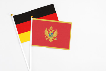 Montenegro and Germany stick flags on white background. High quality fabric, miniature national flag. Peaceful global concept.White floor for copy space.