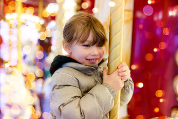 pretty young girl taking a ride in a carousel at christmas