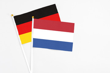 Netherlands and Germany stick flags on white background. High quality fabric, miniature national flag. Peaceful global concept.White floor for copy space.