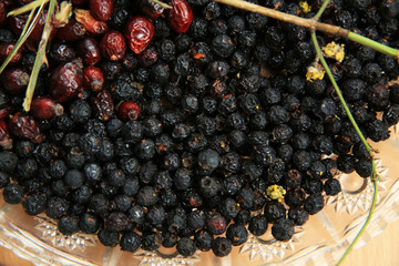 Hawthorn on wooden rustic table background. Rose hips haw fruit of the dog rose. Black chokeberry berries jam .