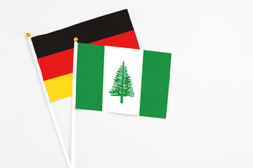 Norfolk Island and Germany stick flags on white background. High quality fabric, miniature national flag. Peaceful global concept.White floor for copy space.