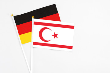 Northern Cyprus and Germany stick flags on white background. High quality fabric, miniature national flag. Peaceful global concept.White floor for copy space.