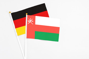 Oman and Germany stick flags on white background. High quality fabric, miniature national flag. Peaceful global concept.White floor for copy space.