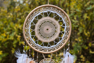 Handgefertigter Traumfänger mit Federn, Fäden und Perlen am Seil hängend © dashtik