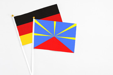 Reunion and Germany stick flags on white background. High quality fabric, miniature national flag. Peaceful global concept.White floor for copy space.