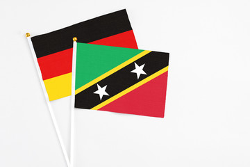 Saint Kitts And Nevis and Germany stick flags on white background. High quality fabric, miniature national flag. Peaceful global concept.White floor for copy space.