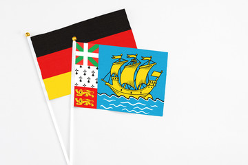 Saint Pierre And Miquelon and Germany stick flags on white background. High quality fabric, miniature national flag. Peaceful global concept.White floor for copy space.