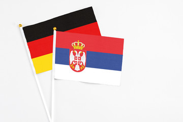 Serbia and Germany stick flags on white background. High quality fabric, miniature national flag. Peaceful global concept.White floor for copy space.