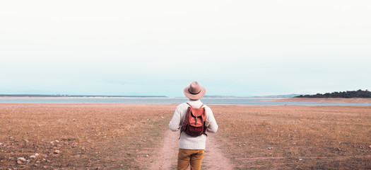 young man traveling through nature with backpack and hat - 302687966